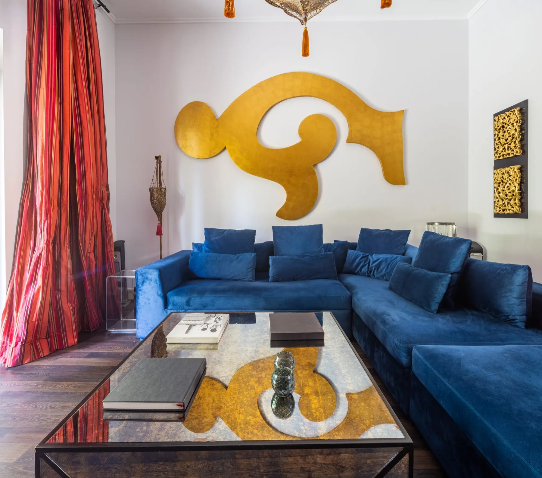 Una sala de estar con asientos seccionales azules y una mesa de centro de vidrio.