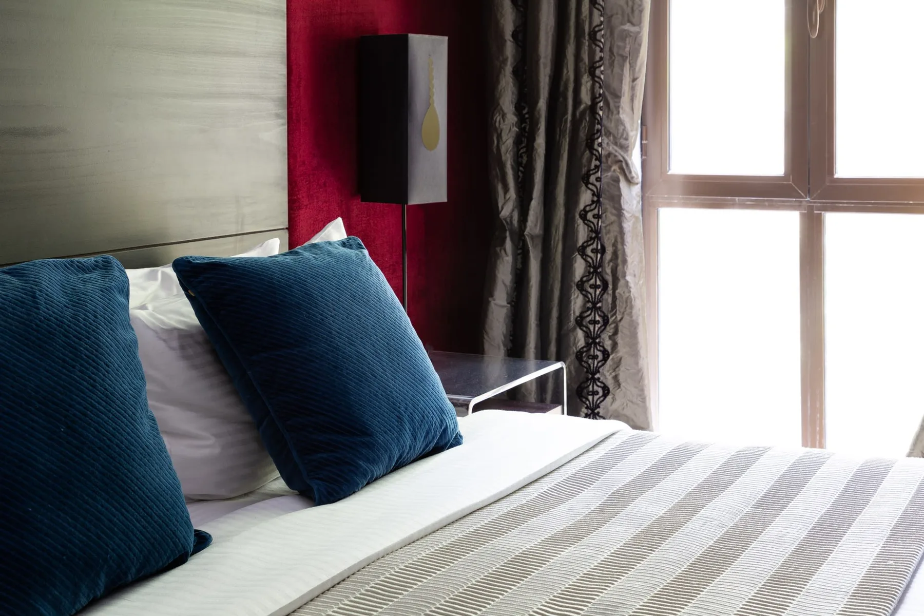 A bedroom with a bed, blue pillows, and a large window.