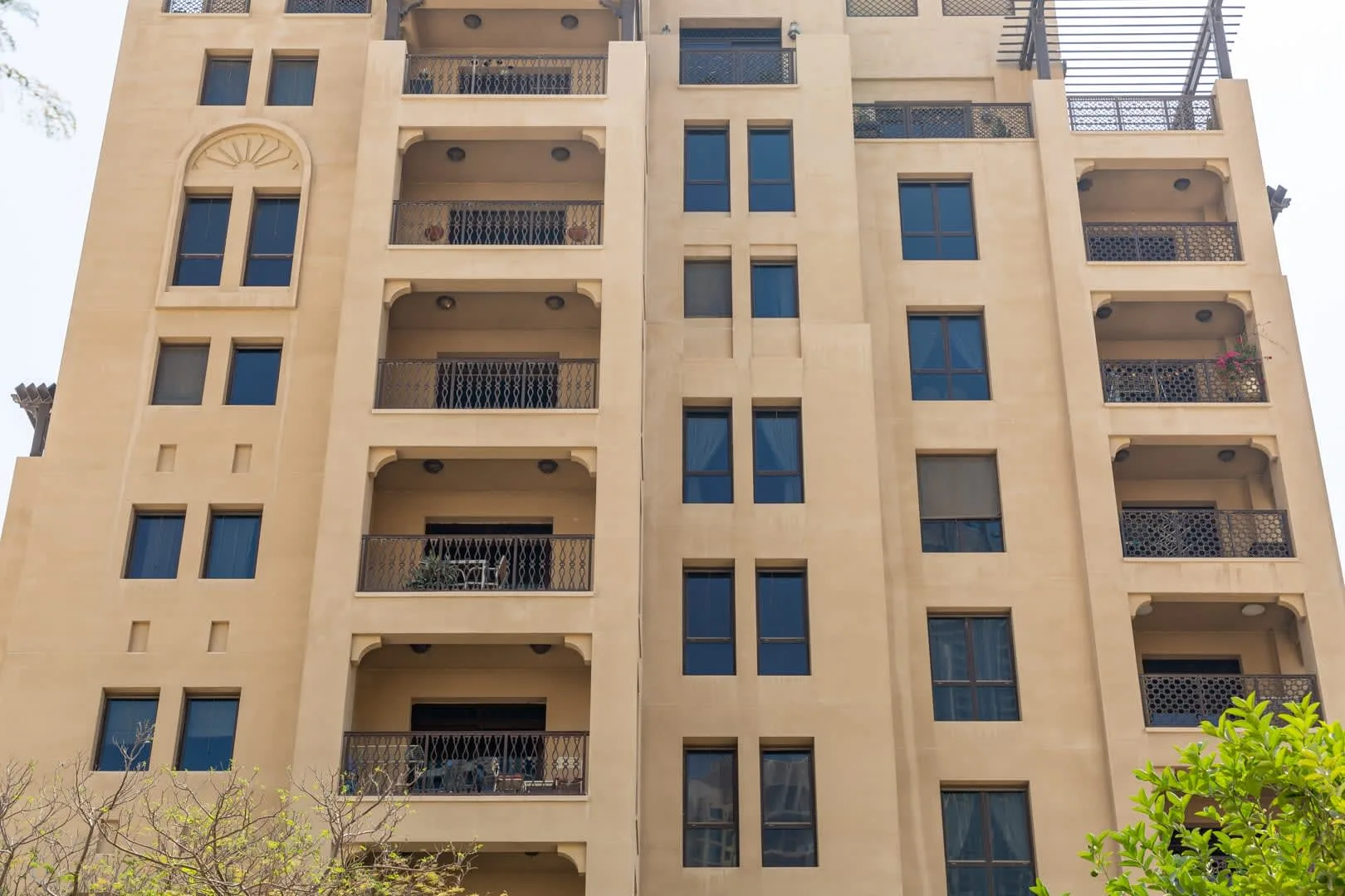 A beige apartment building facade with rows of windows and balconies.
