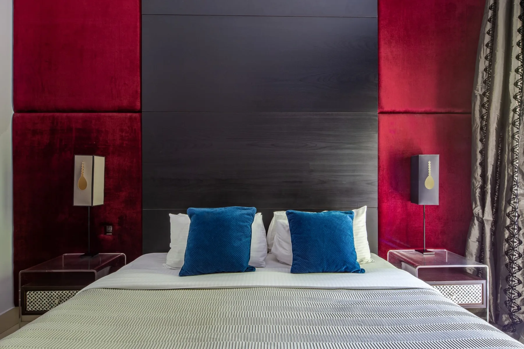 A bedroom with a neatly made bed and blue accent pillows.