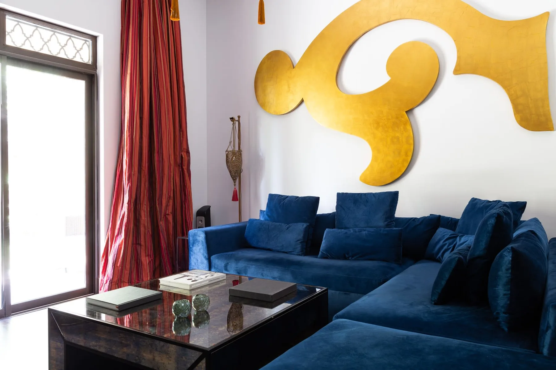 A living room with deep blue seating and a large gold wall decoration.
