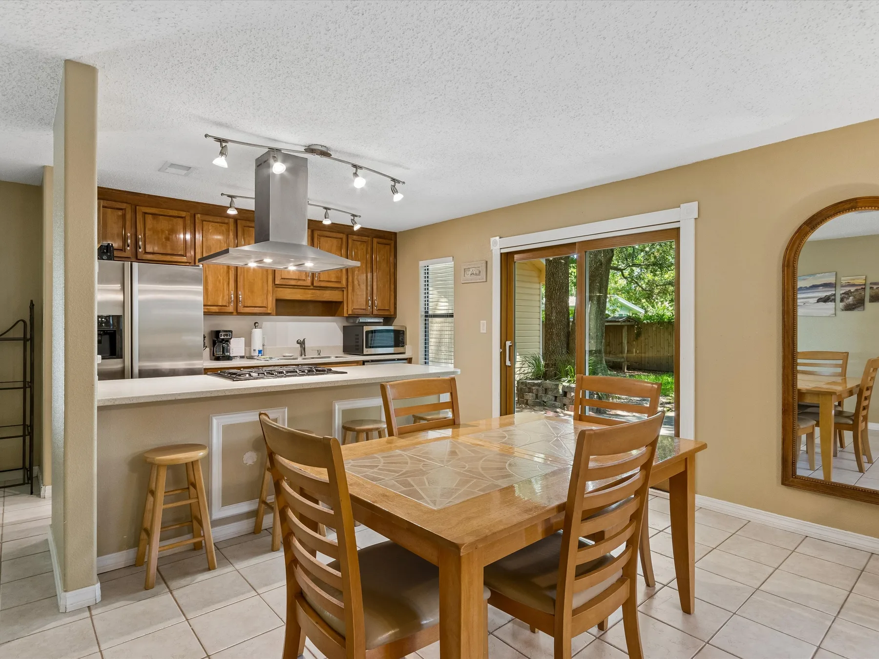 A dining area with a wooden table and chairs beside an open kitchen.