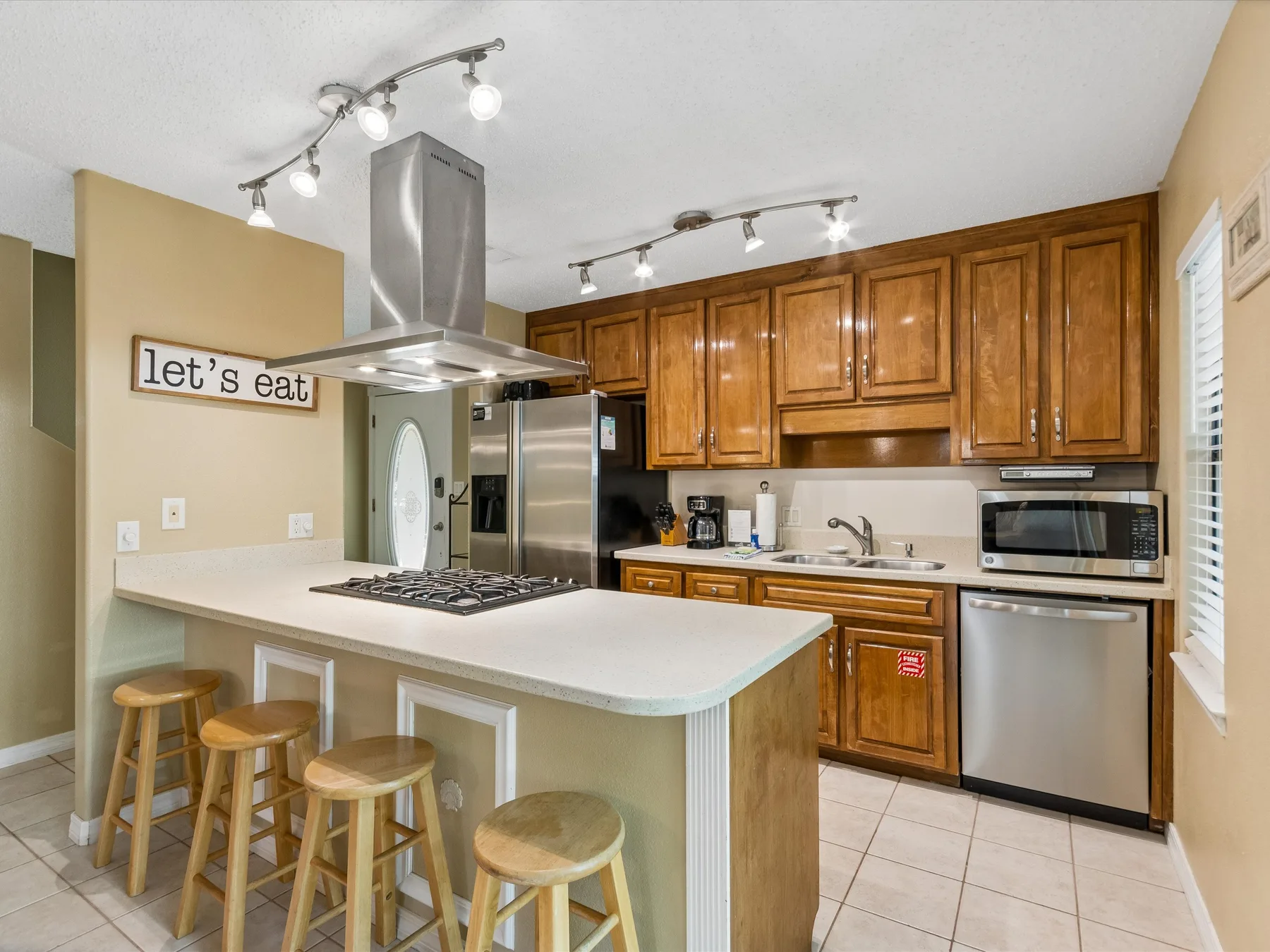 A kitchen with a large island, wooden cabinets, and stainless steel appliances.