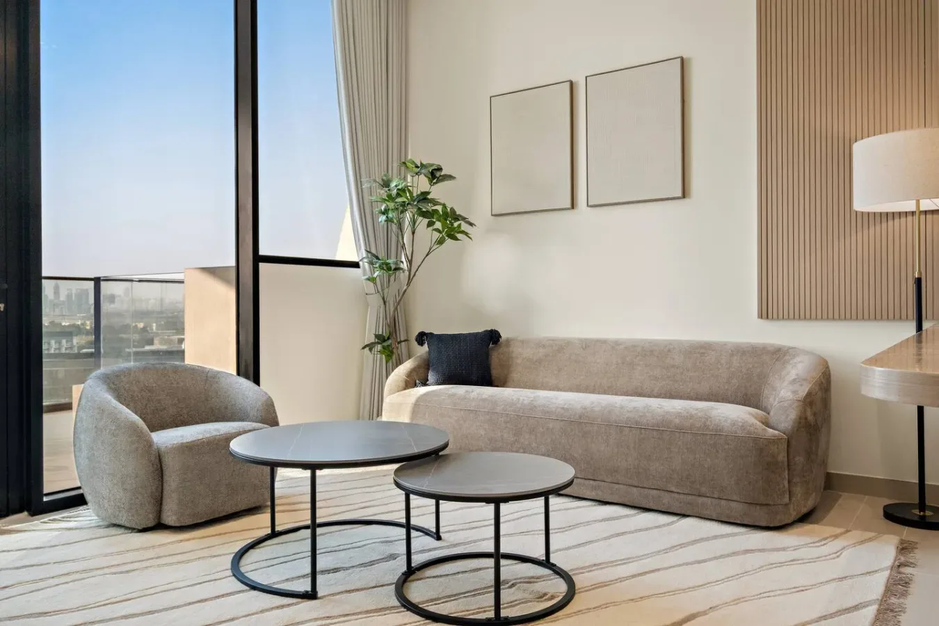 Una sala luminosa con sofá, sillón y ventanales.