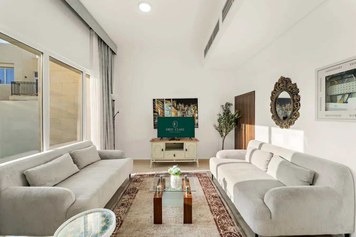 Una sala luminosa con asientos claros dispuestos alrededor de una mesa de centro de vidrio.