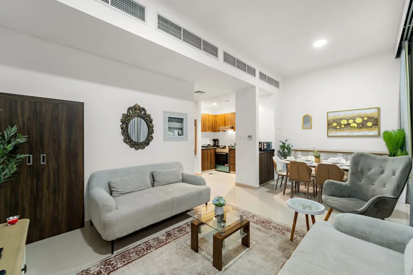 Una luminosa sala de estar y comedor con asientos, una mesa de centro de vidrio y una mesa de comedor.