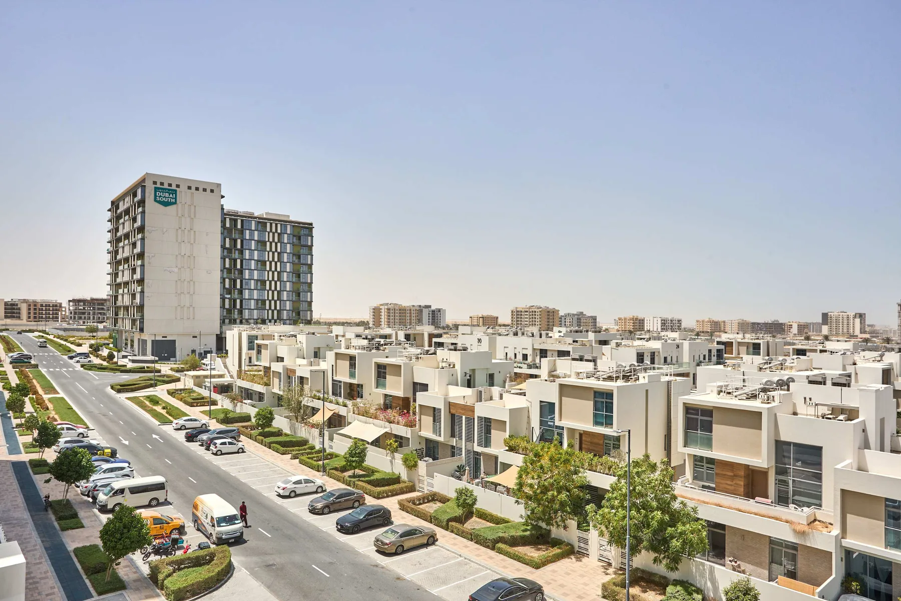 A residential neighborhood with modern low-rise buildings and a taller apartment block.