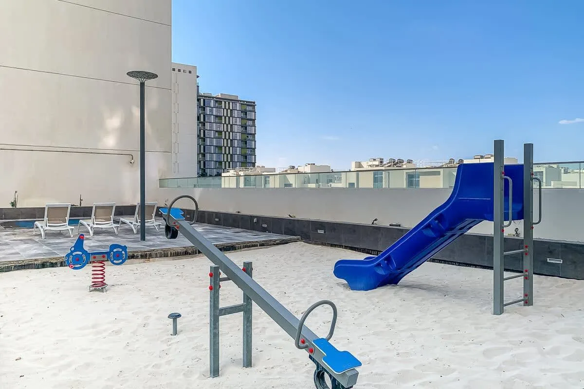 An outdoor playground with a blue slide and spring-mounted play equipment.