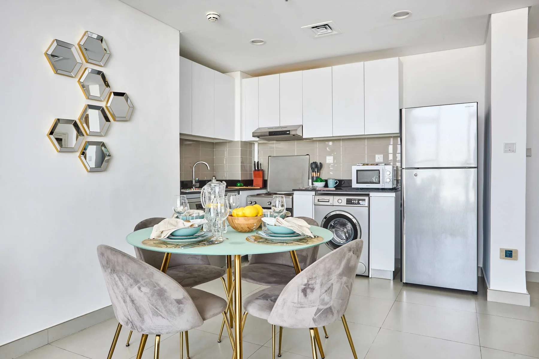 A bright kitchen with white cabinets, appliances, and a dining table set with dishes.