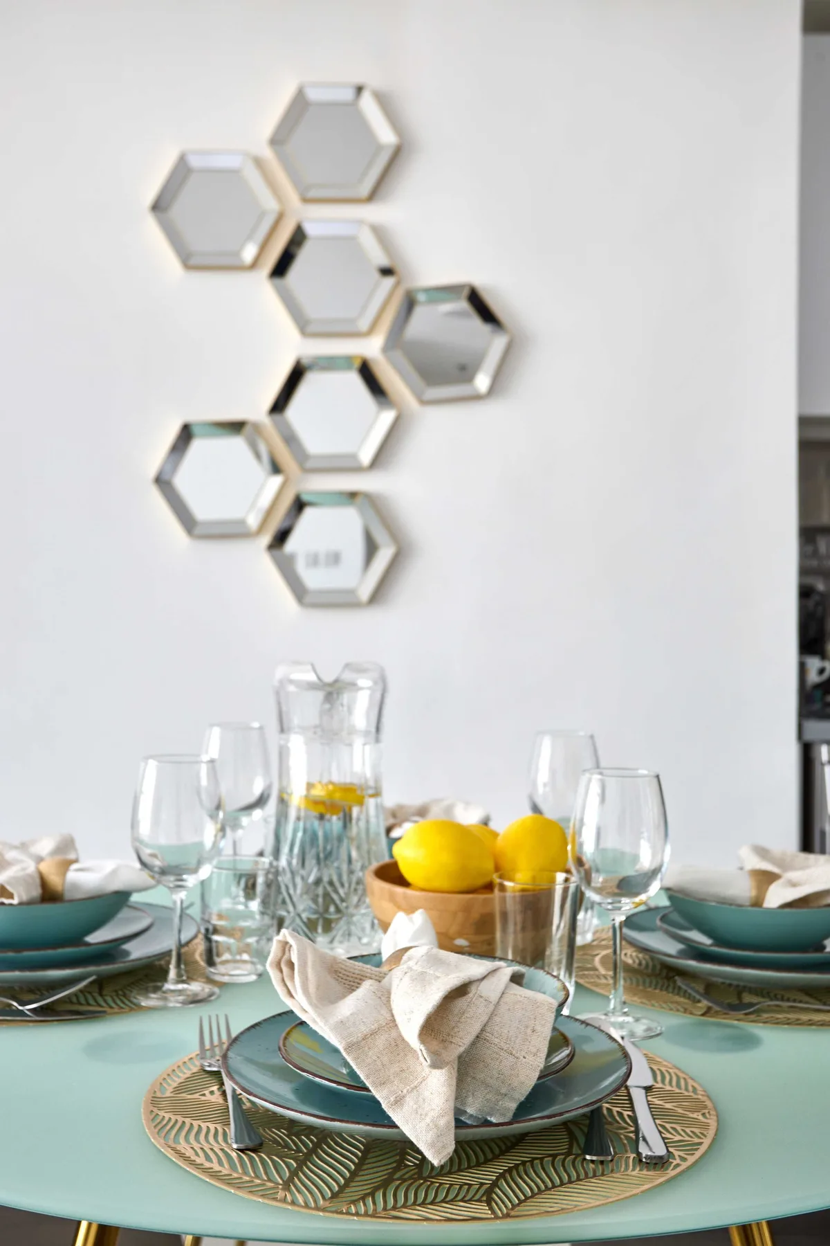 A dining table is set with plates, glasses, and a bowl of lemons.