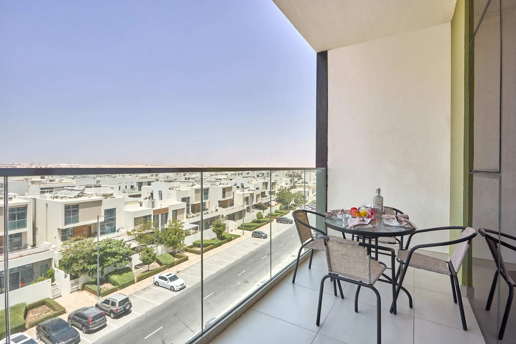 A balcony with outdoor seating overlooks a residential neighborhood.