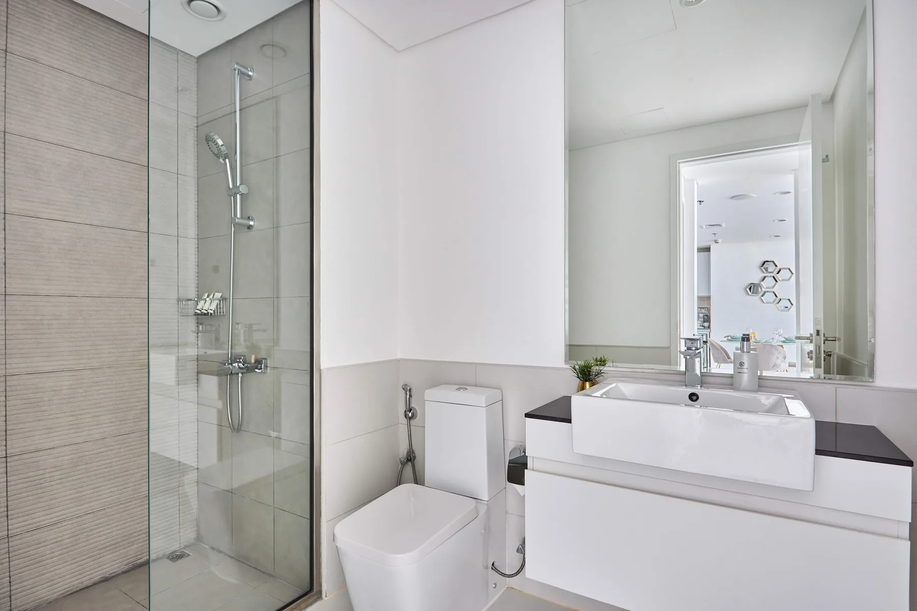 A bright bathroom with a glass shower and a sink beneath a large mirror.
