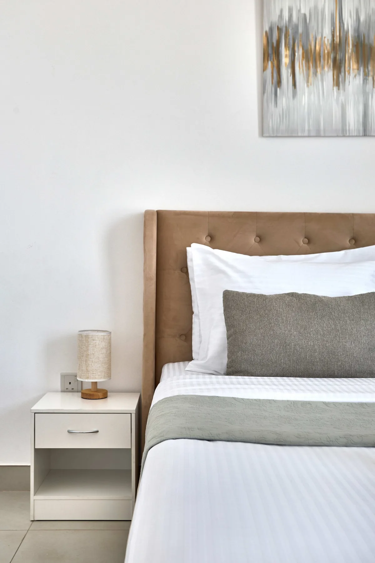 A bedroom with a neatly made bed and a bedside table.