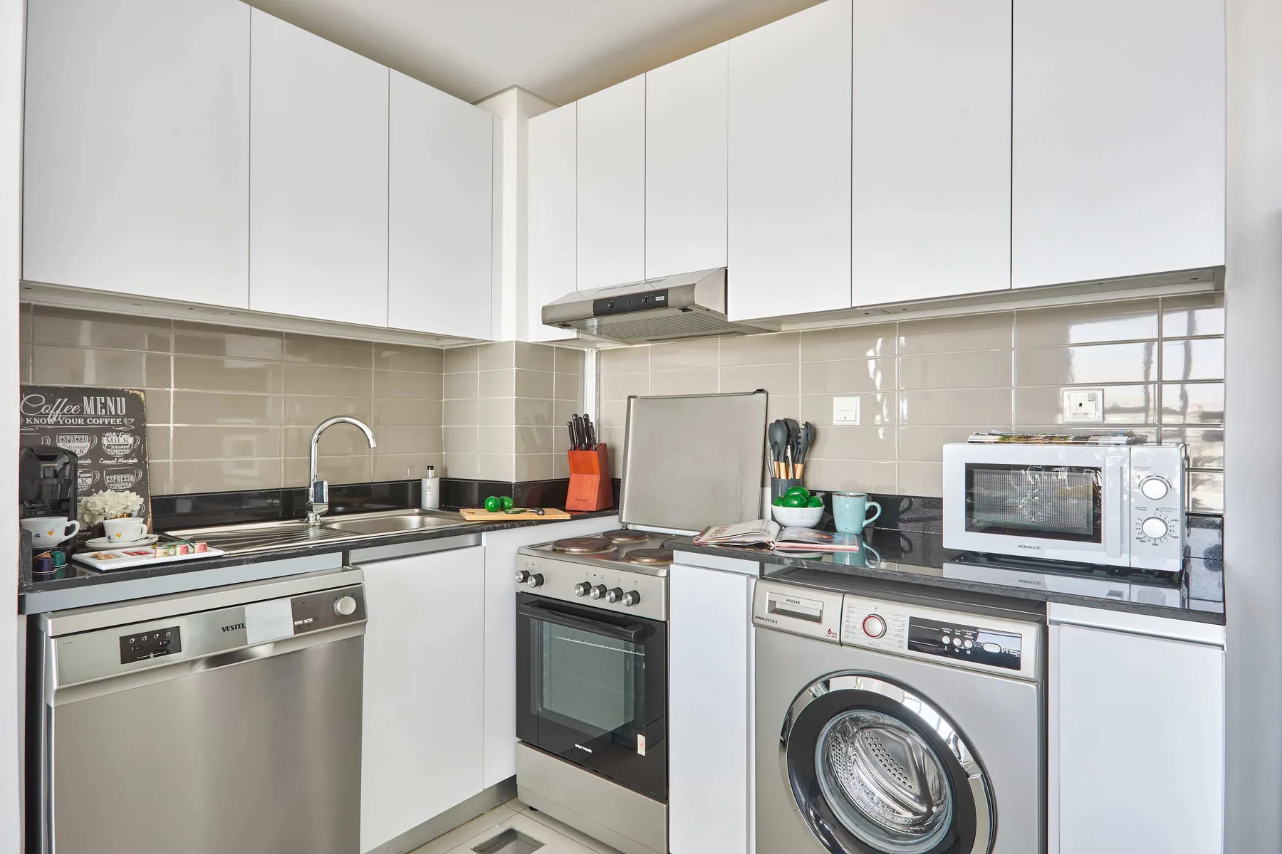 A bright kitchen with white cabinets, a stove, and a washing machine.