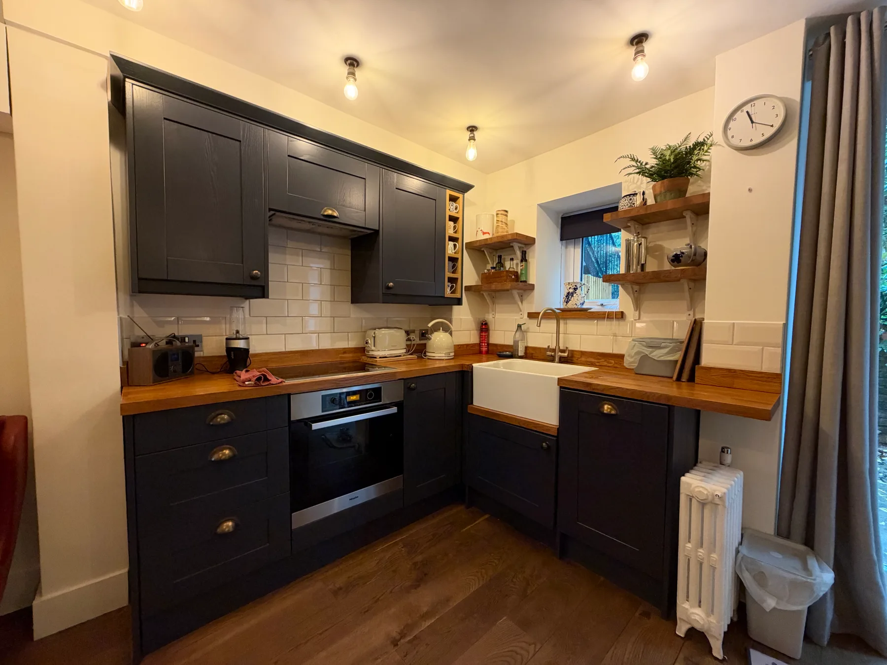 A compact kitchen with dark cabinets, wooden countertops, and a window.