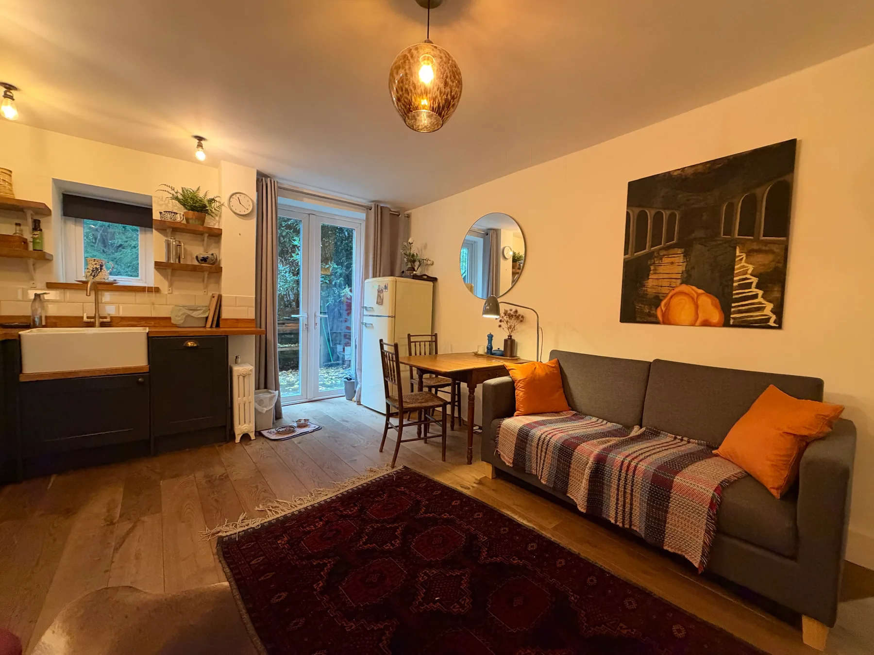 A compact living room with a kitchenette, dining table, and gray seating.