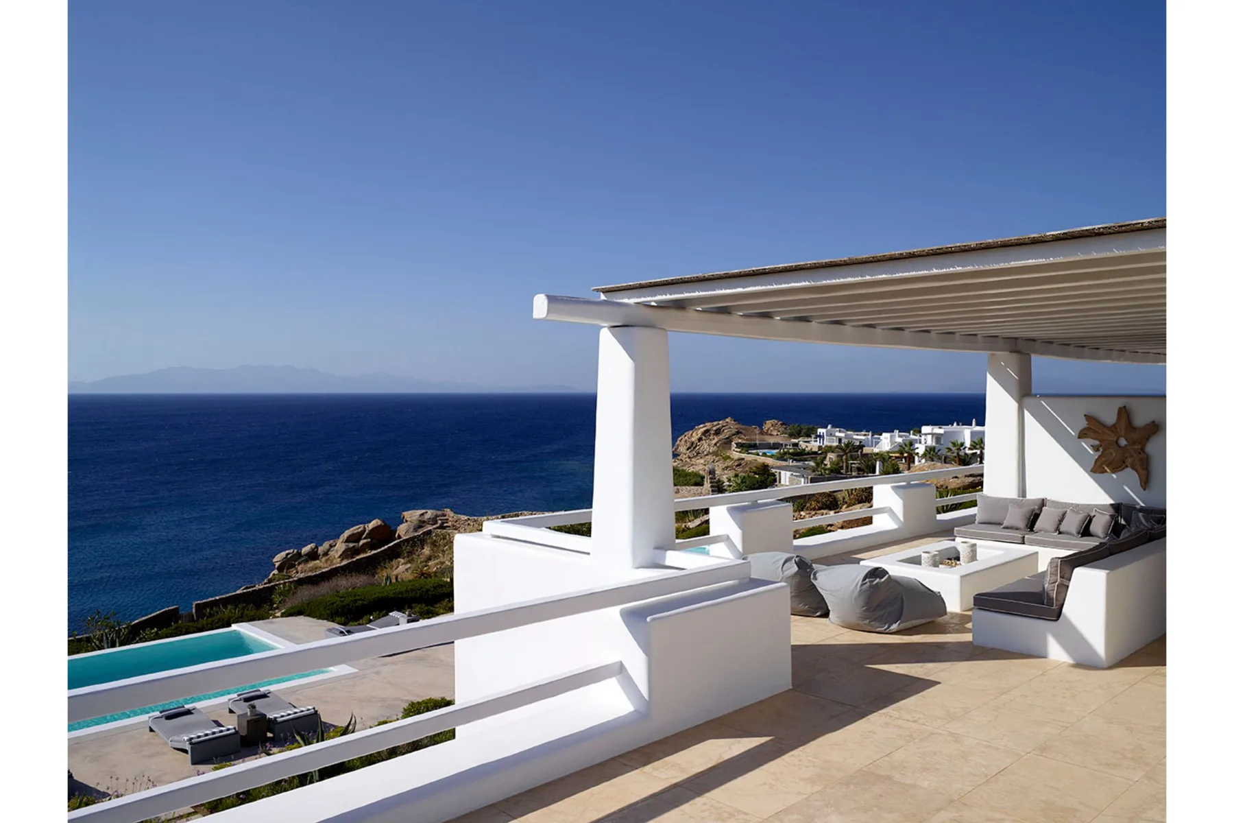 A seaside terrace overlooks the ocean, with built-in seating and a swimming pool.