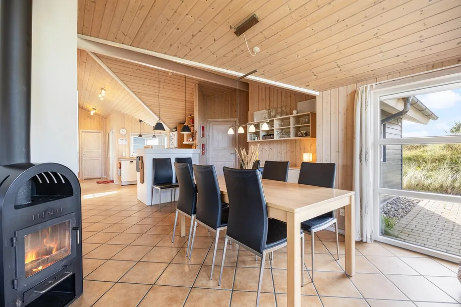 Un comedor con paneles de madera, una mesa y una estufa negra.