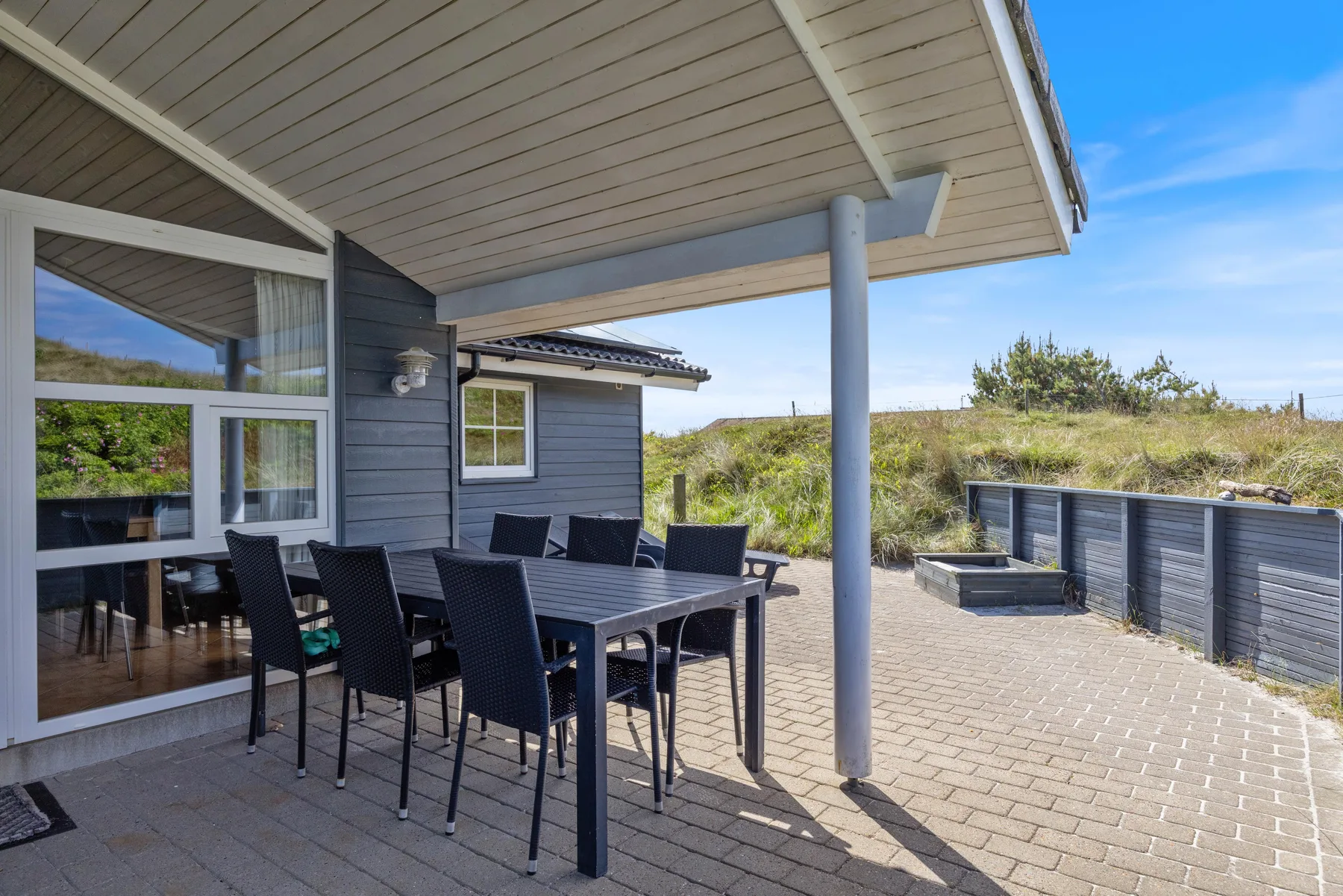 Un patio cubierto con muebles de comedor al aire libre junto a una casa.