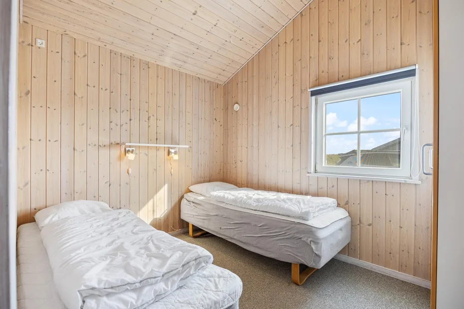 Un dormitorio con dos camas bajo un techo inclinado revestido de madera.