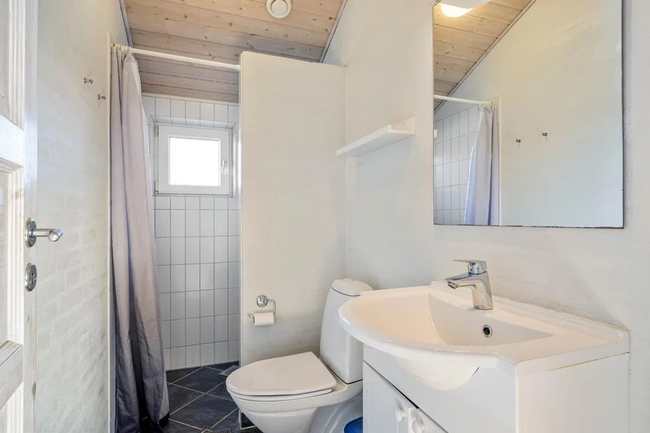 Un baño con lavabo, inodoro y ducha con cortina.