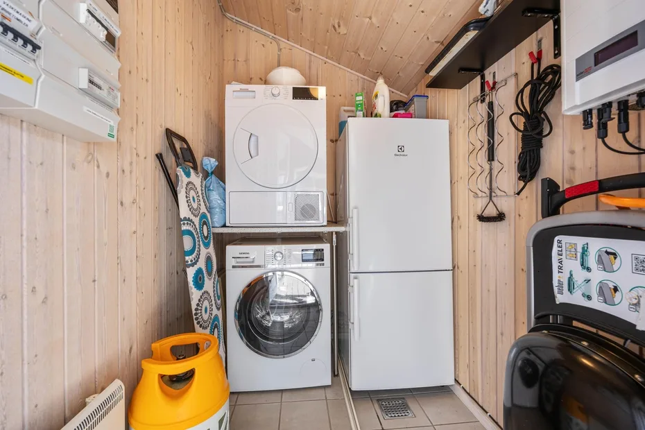 Un pequeño cuarto de lavandería y servicio con lavadora, secadora y refrigerador.