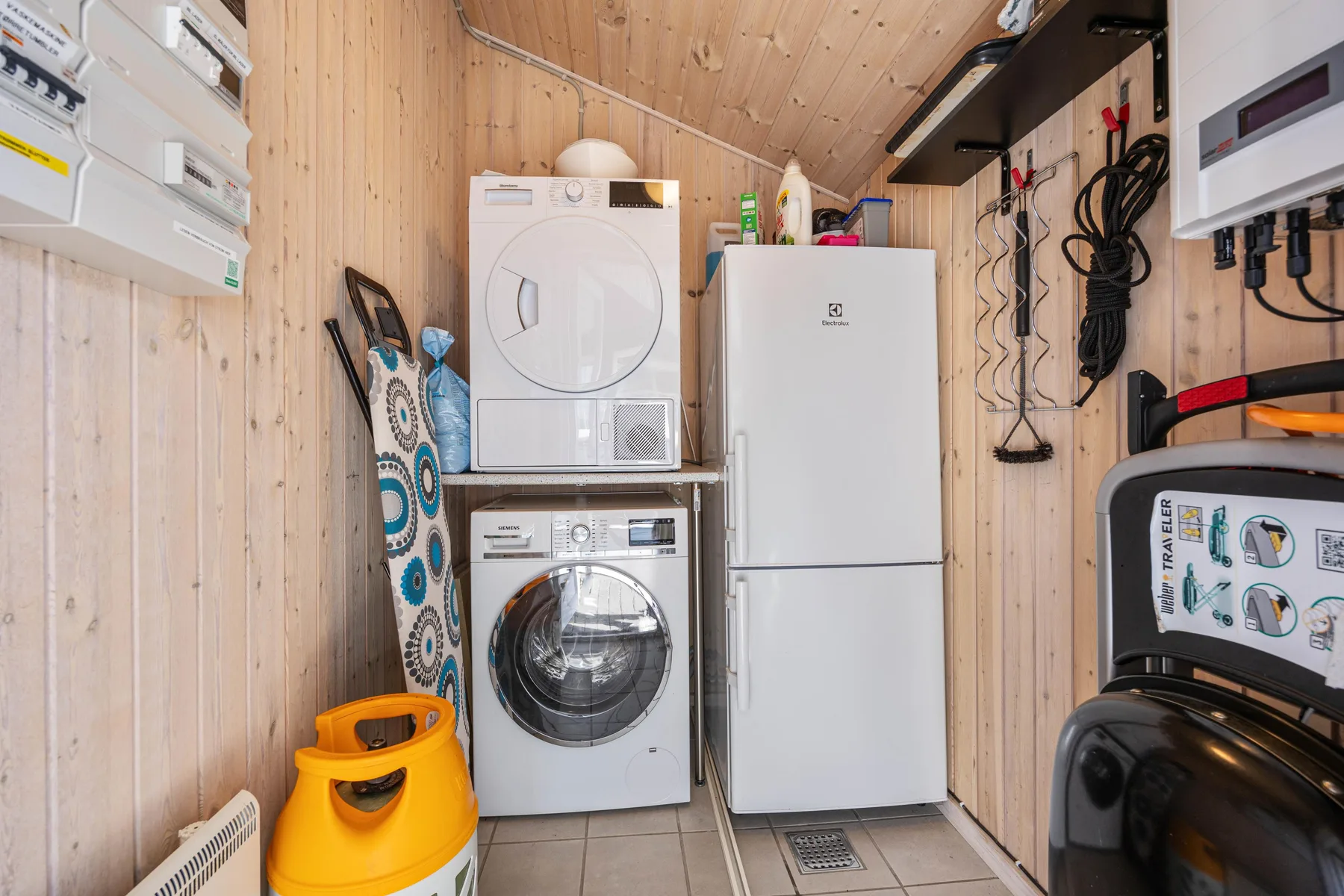 Un cuarto de lavandería compacto con lavadoras apiladas y un refrigerador.