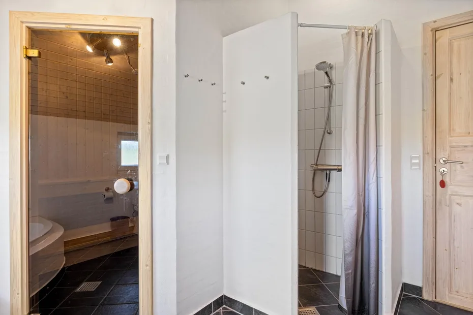 Un baño con ducha y una zona de baño alicatada separada.