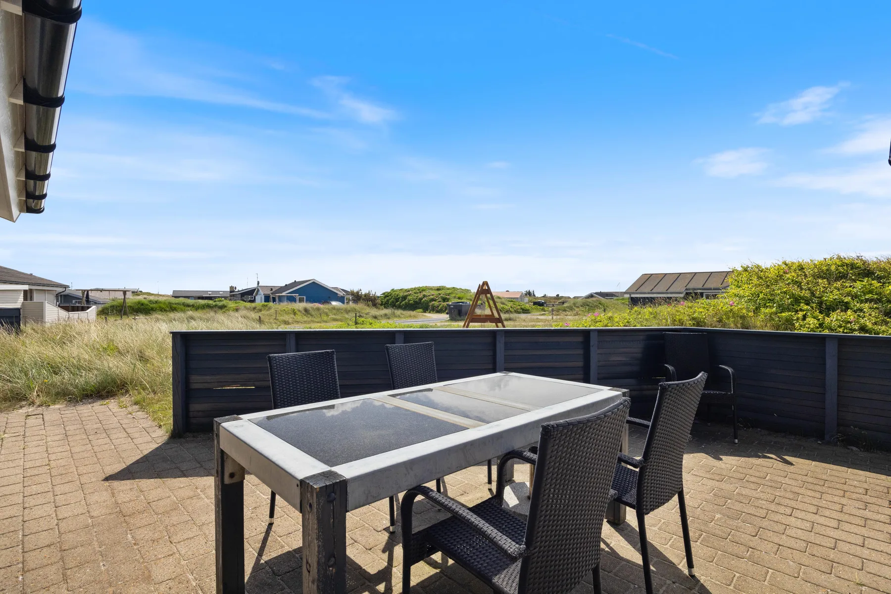 Una zona de comedor al aire libre con una mesa y asientos junto a una cerca oscura.