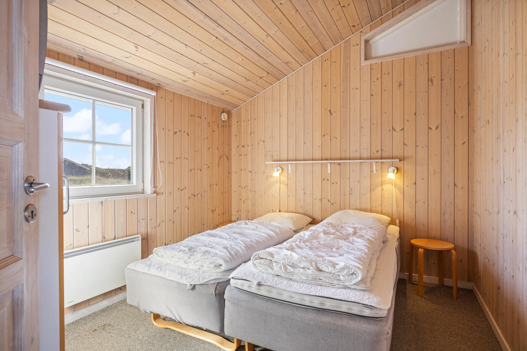 Un dormitorio con dos camas bajo un techo de madera inclinado.