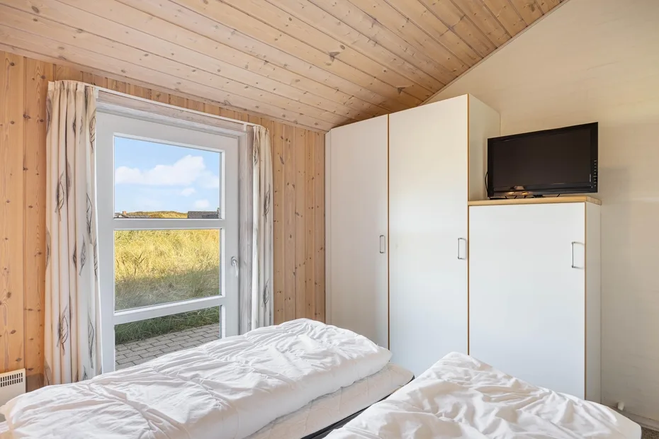 Un dormitorio con camas junto a una ventana y armarios empotrados.