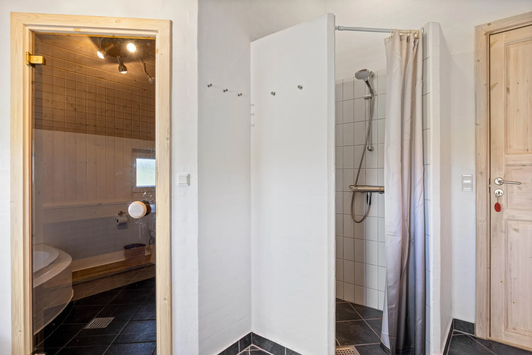 Un baño con una ducha junto a una sauna con azulejos.
