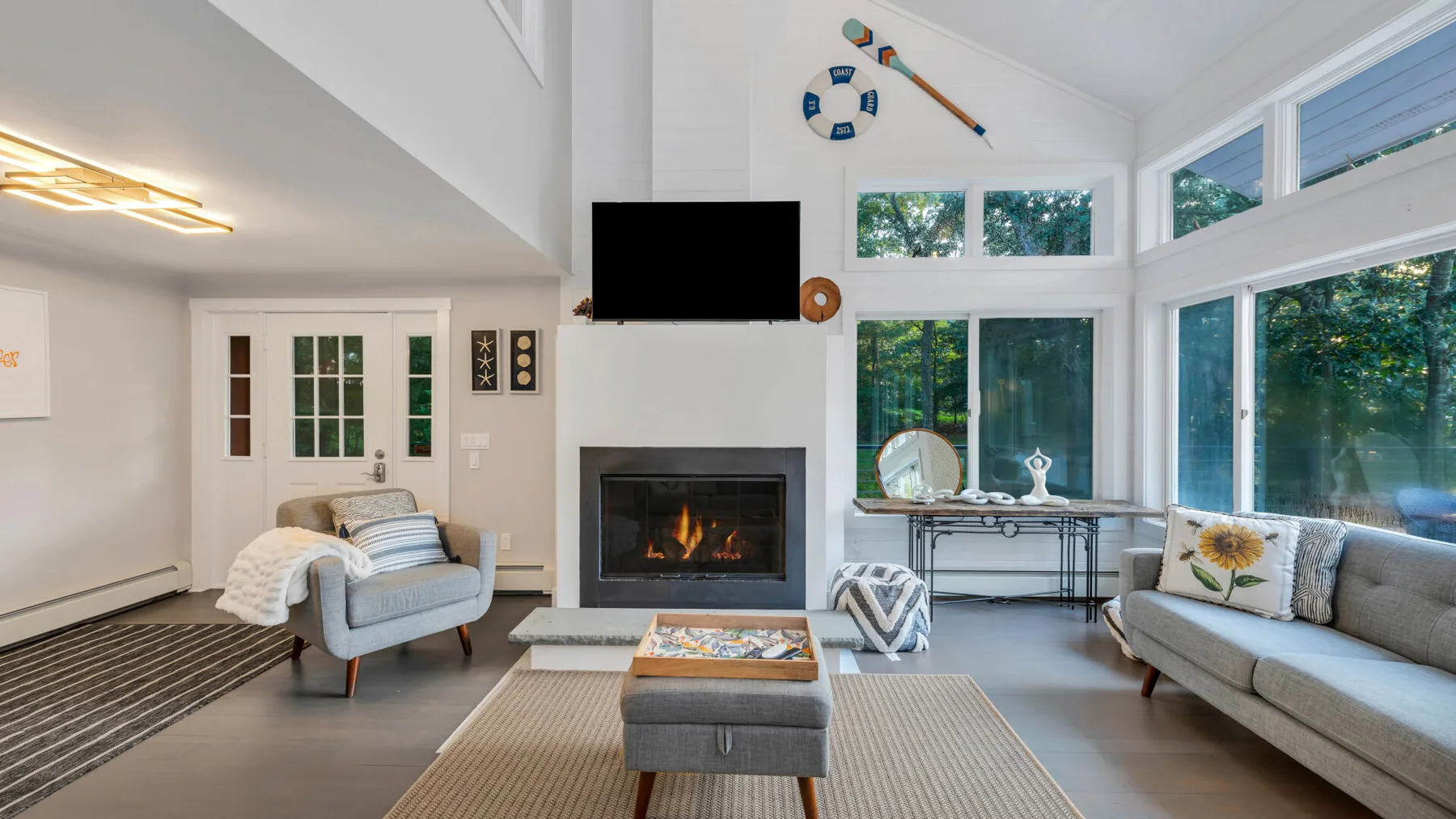 A bright living room with a fireplace, seating, and large windows.