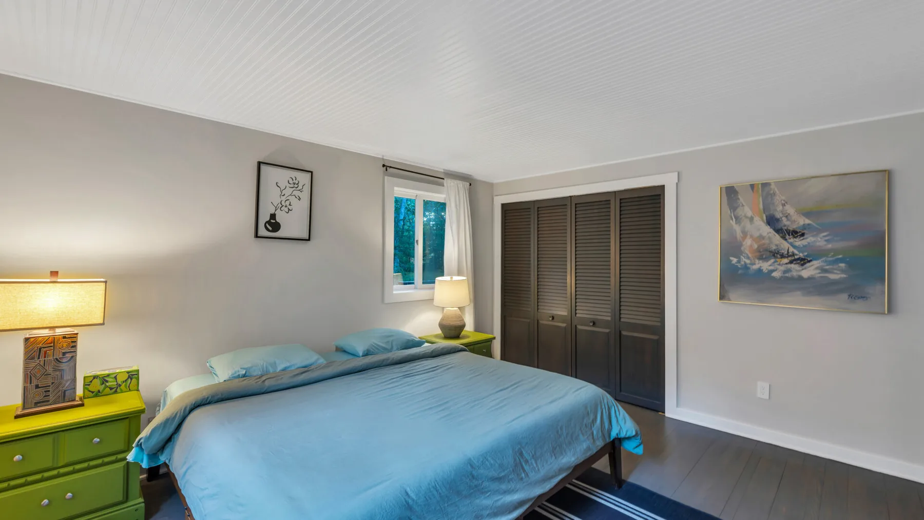 A bedroom with a bed, bedside lamps, and a dark wardrobe.
