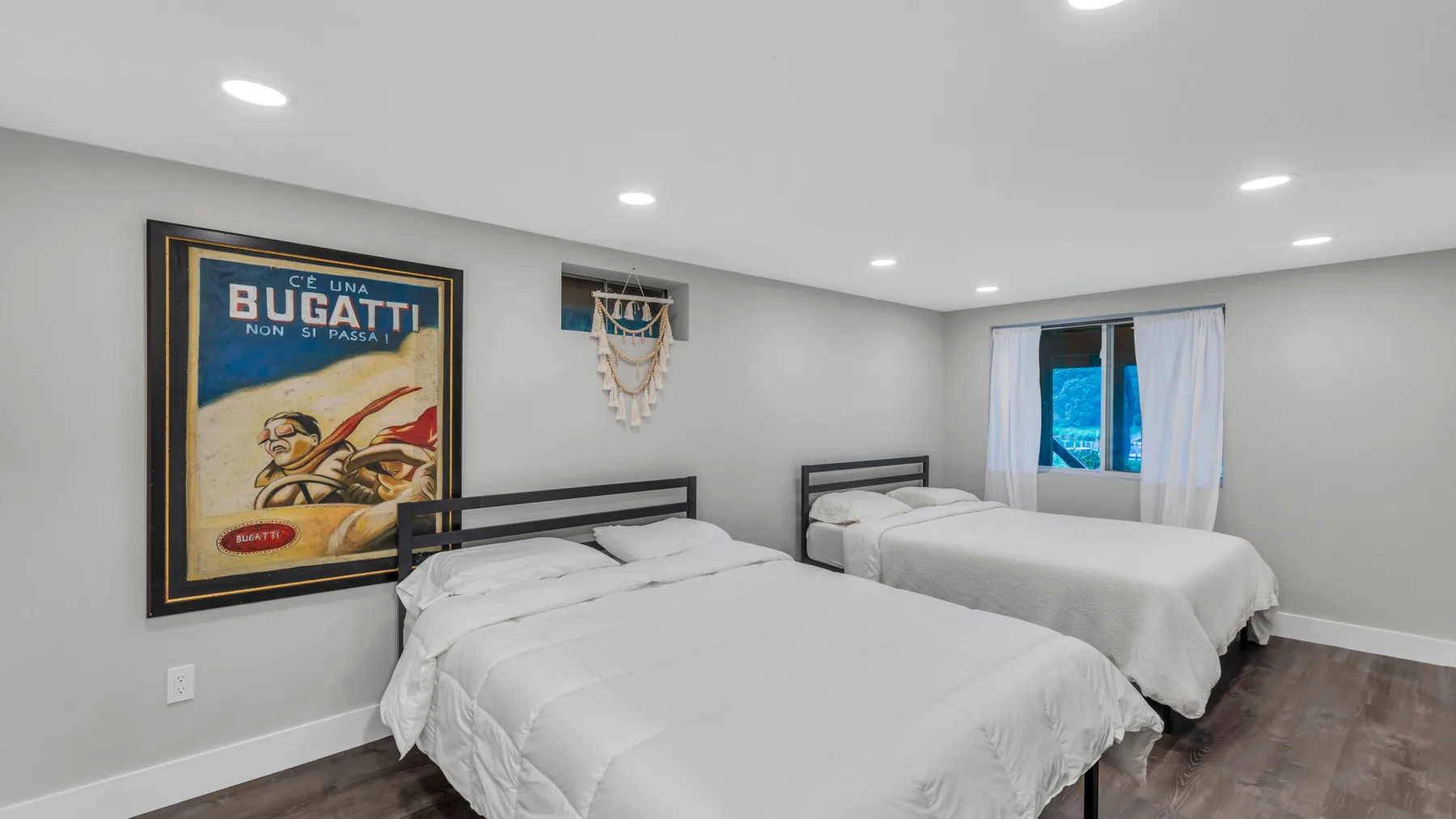 A bedroom with two beds, white bedding, and a framed poster on the wall.