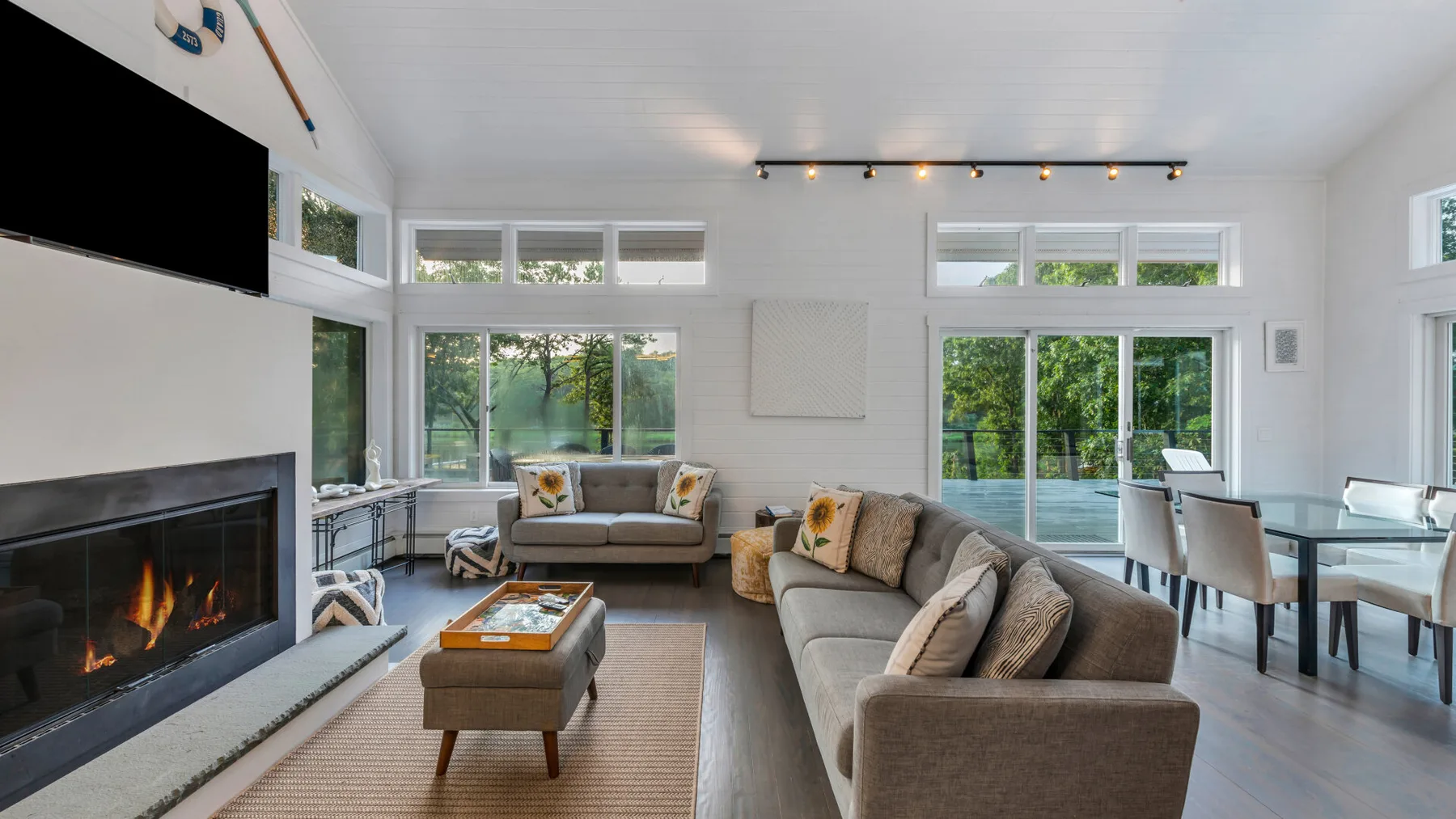 A bright living and dining area features seating beside a large window.
