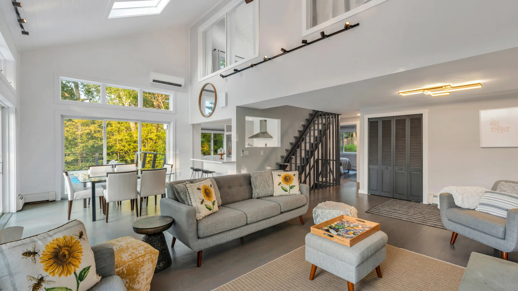 A bright living room with seating, a coffee table, and large windows.