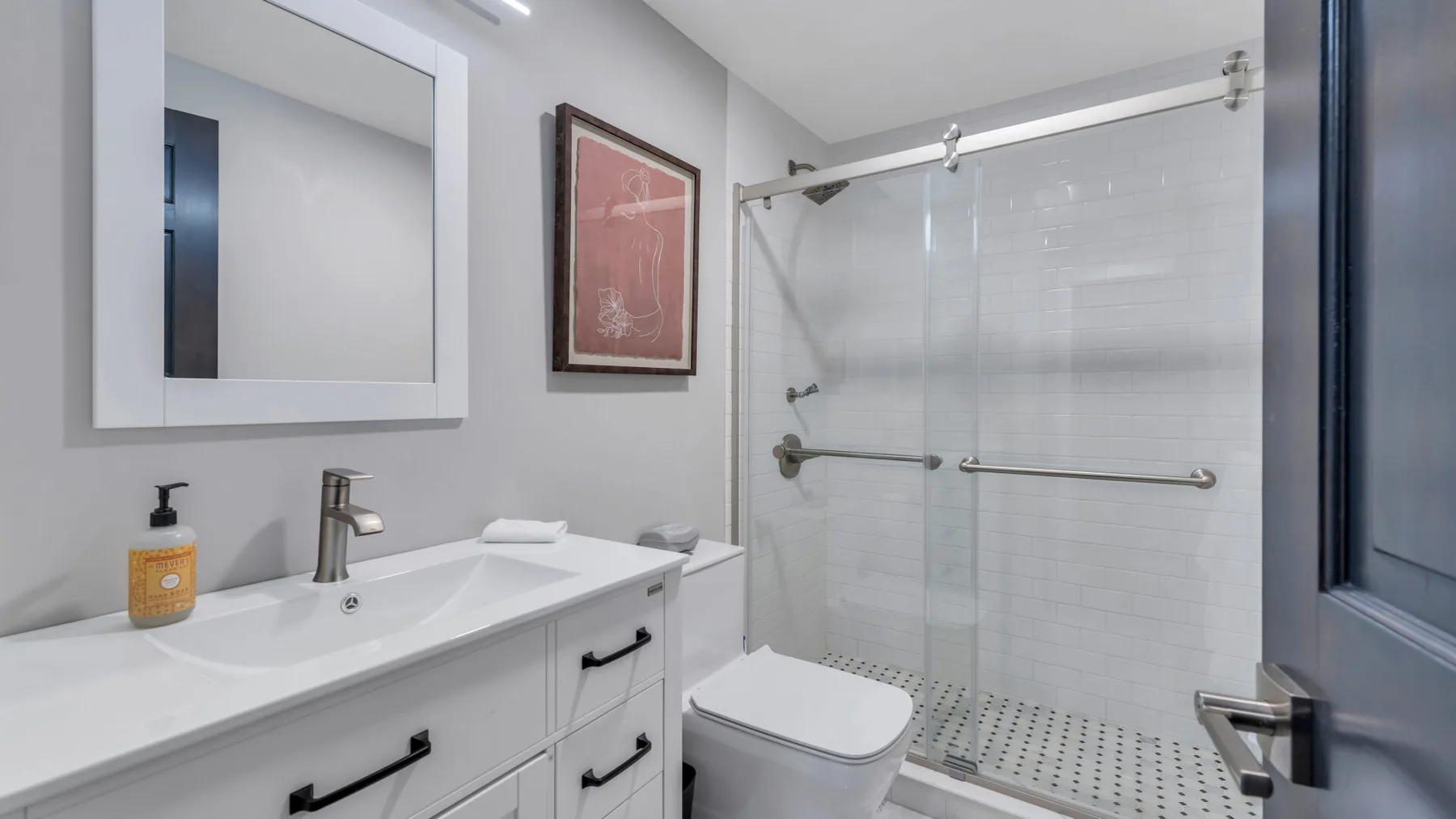 A bright bathroom with a sink vanity and a glass-enclosed shower.