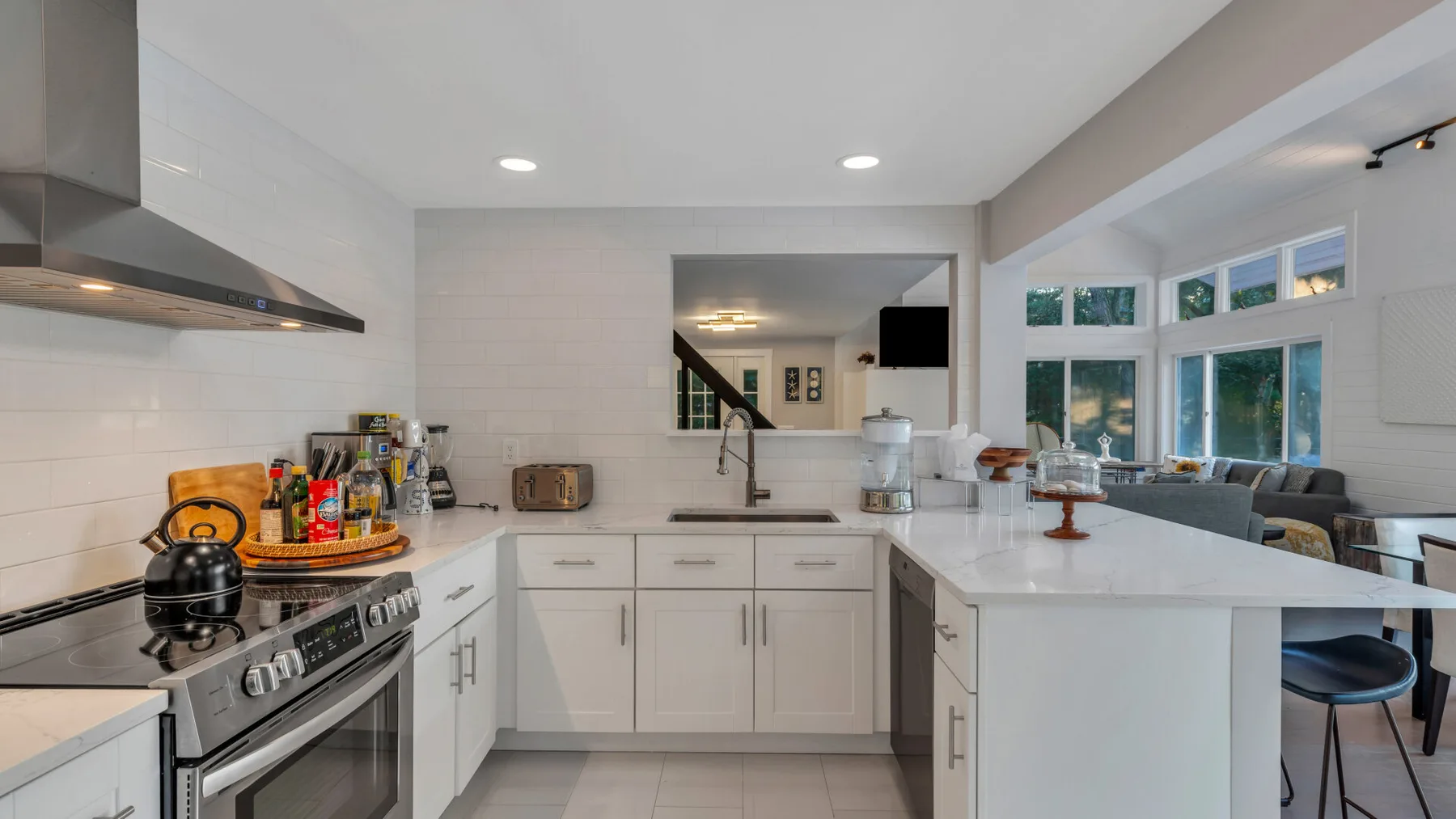 A bright kitchen with white cabinetry and a central island beside large windows.