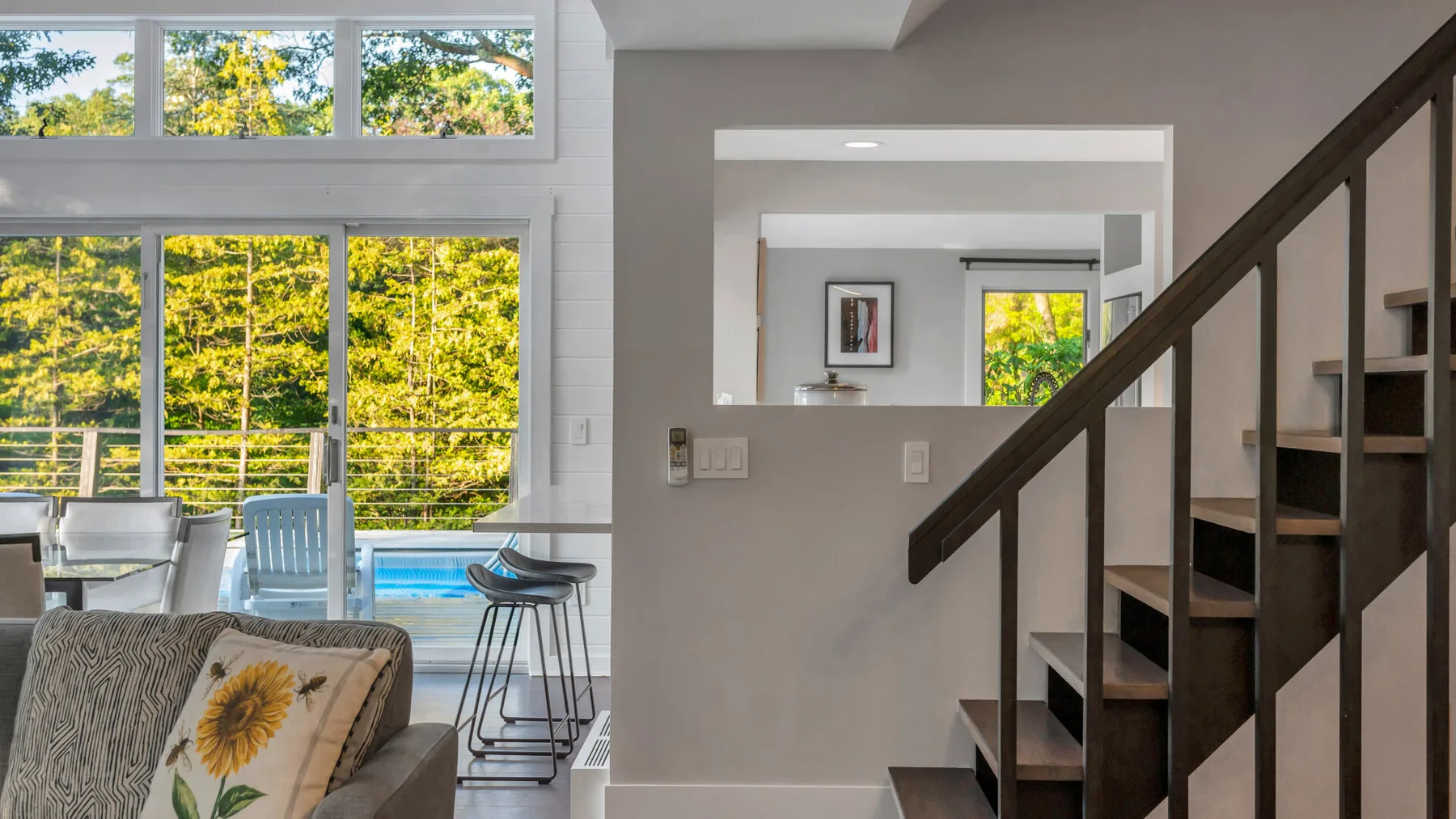 A bright living area with large windows and a staircase.