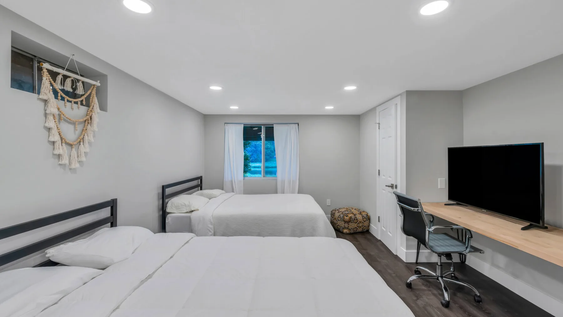 A bedroom with two beds, a desk, and a television.