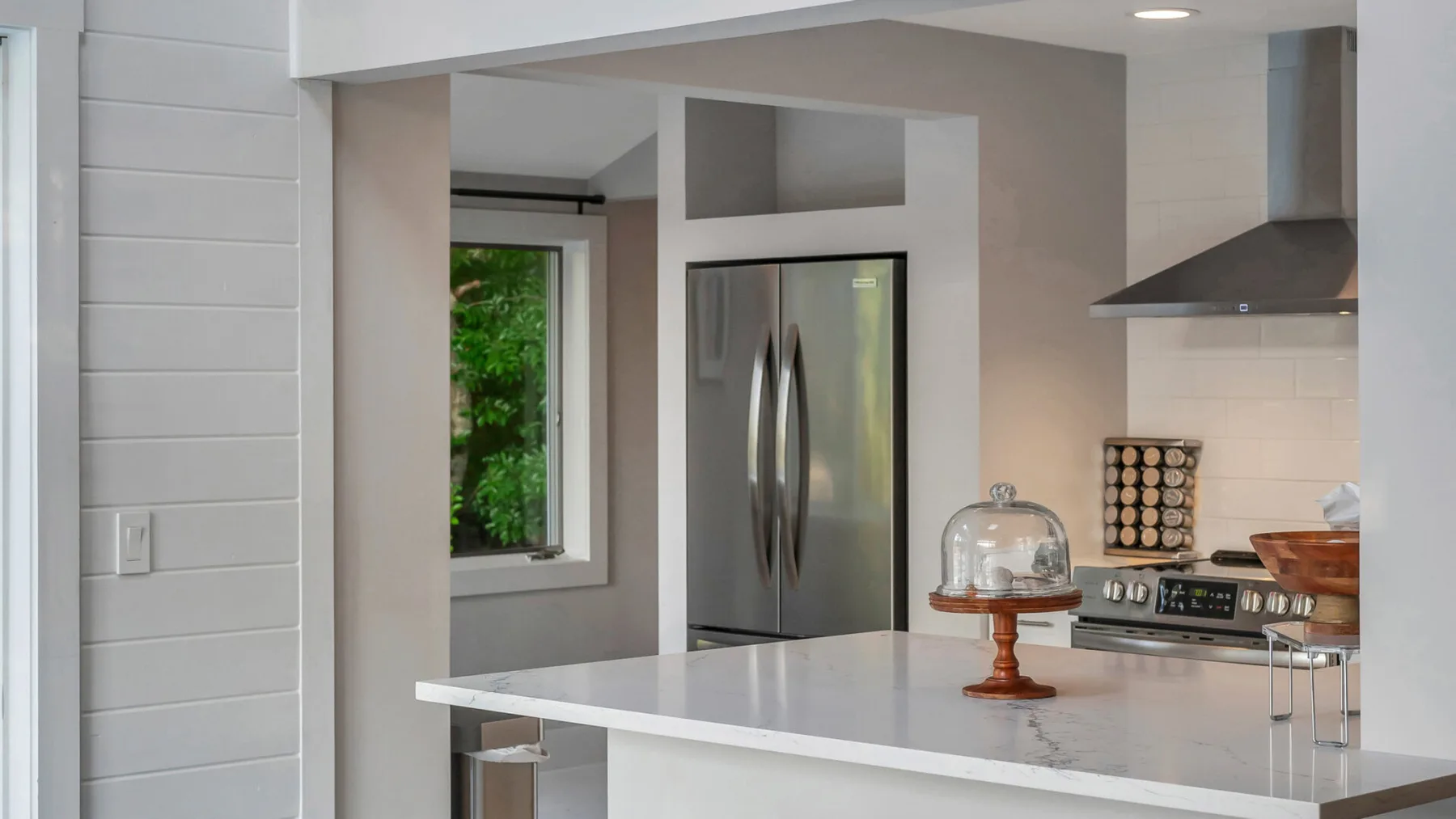 A modern kitchen with a stainless steel refrigerator and a white island.