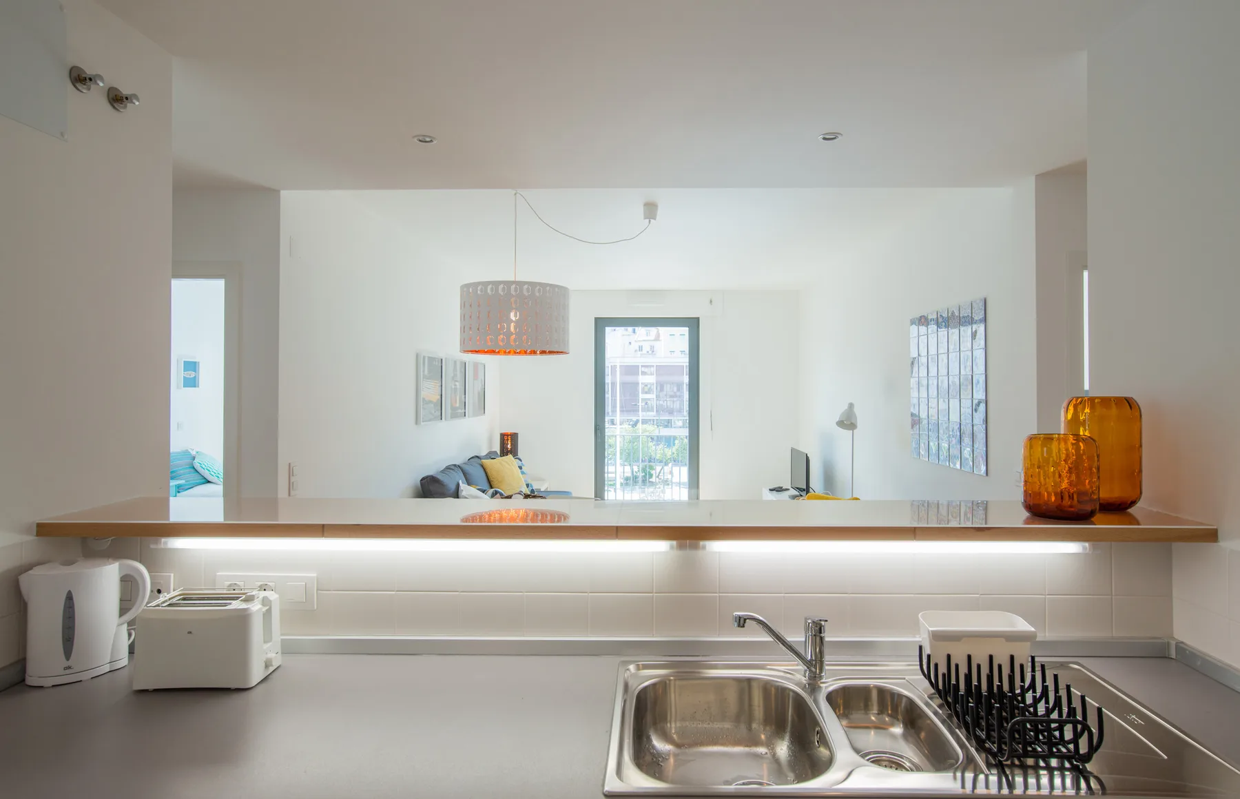 Una cocina luminosa con fregadero y pequeños electrodomésticos sobre la encimera.