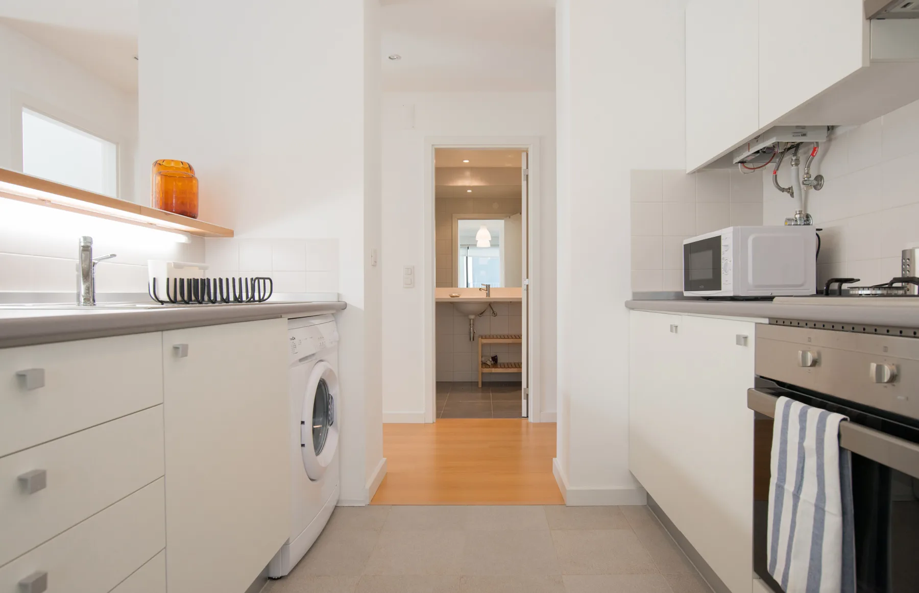 A bright kitchen with white cabinets and a washing machine.