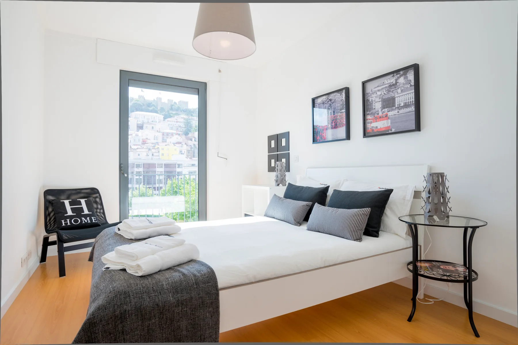 A bright bedroom with a neatly made bed and framed artwork on the wall.