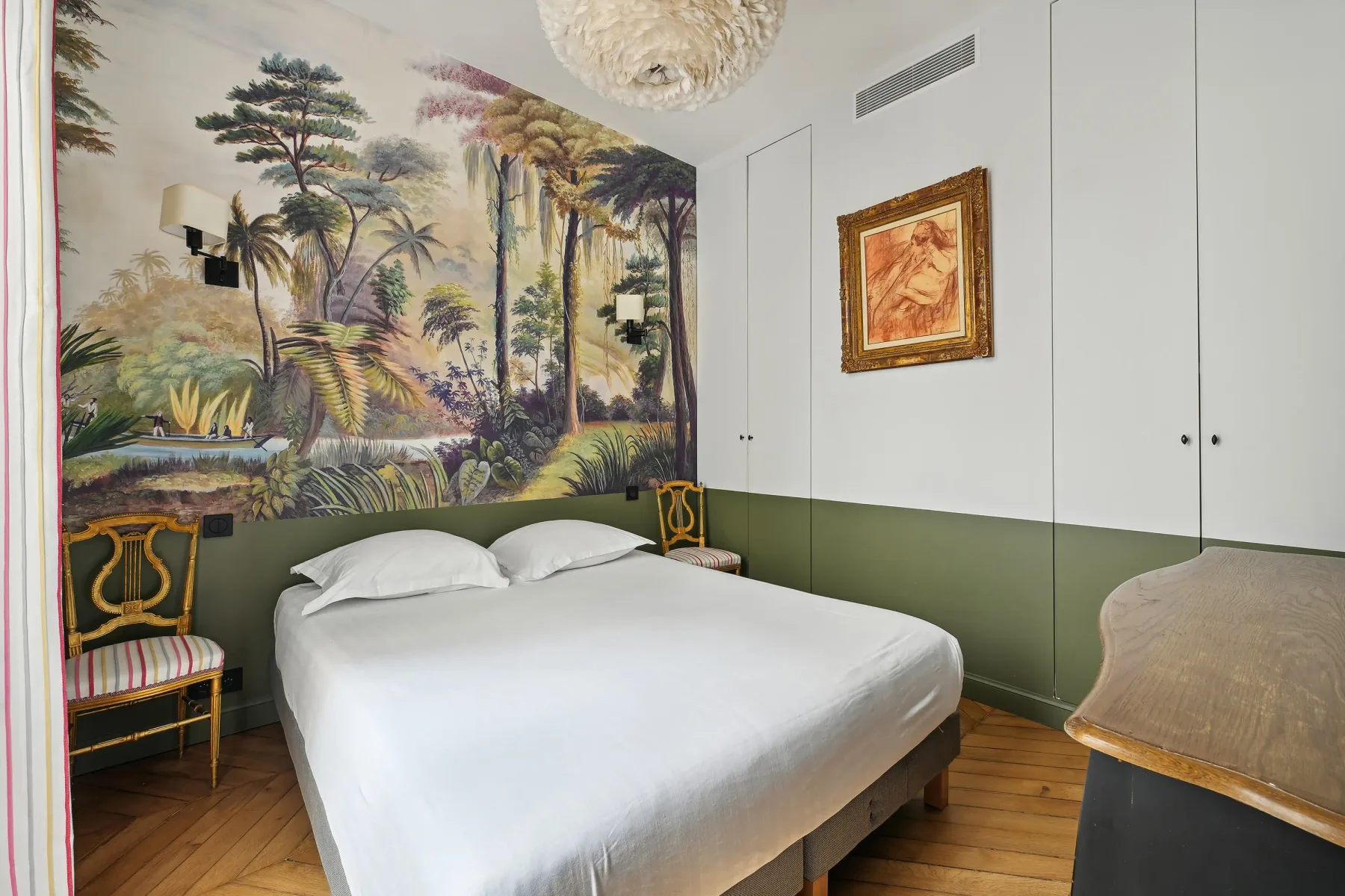 Un dormitorio con una cama, un mural selvático y armarios empotrados.