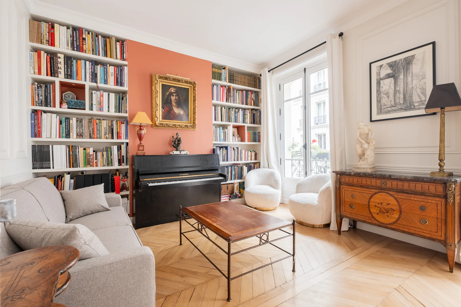 Una sala luminosa con estanterías, un piano, asientos y ventanales altos.