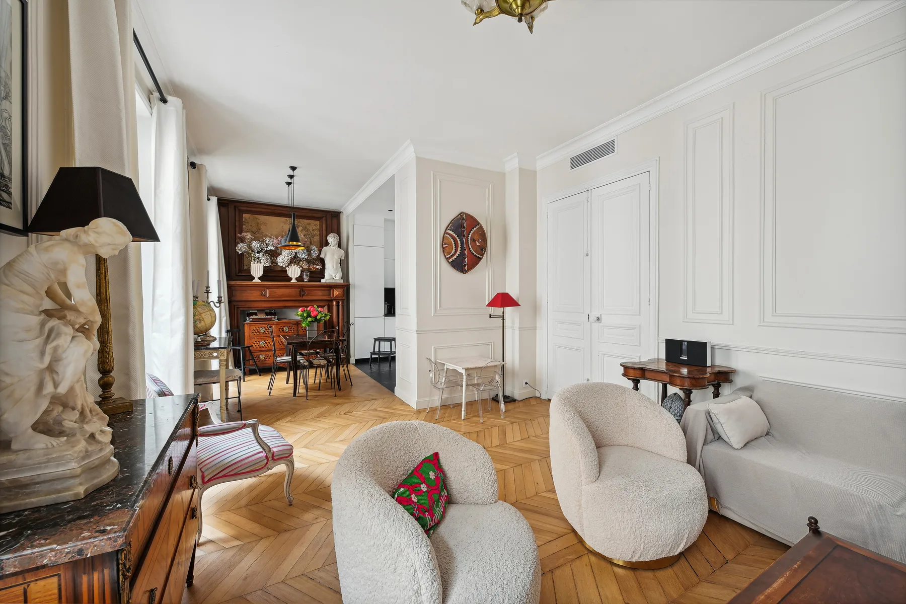 Una sala luminosa con asientos, un comedor y suelo de parquet.