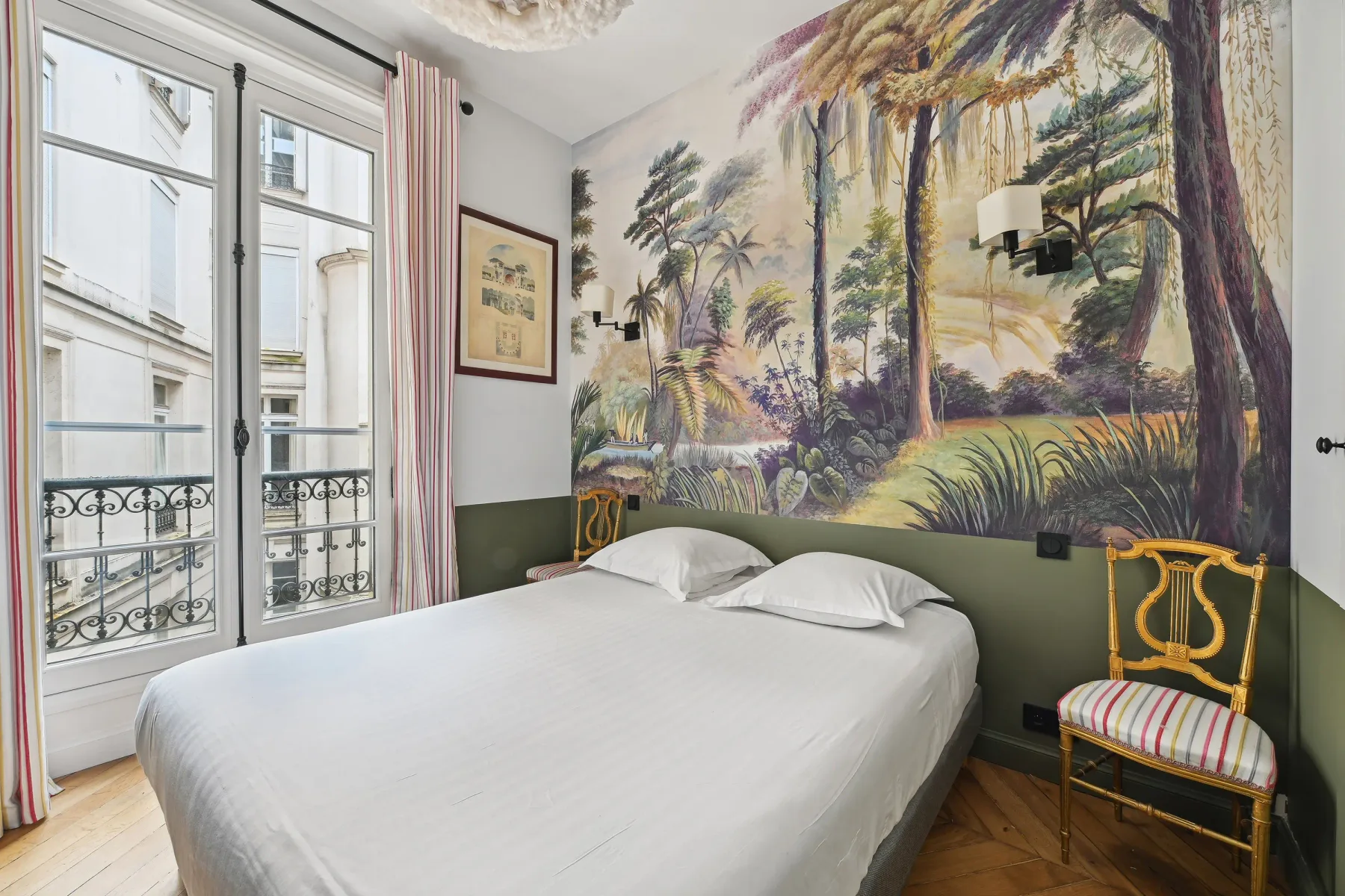 Dormitorio con cama blanca, mural y ventanas altas.