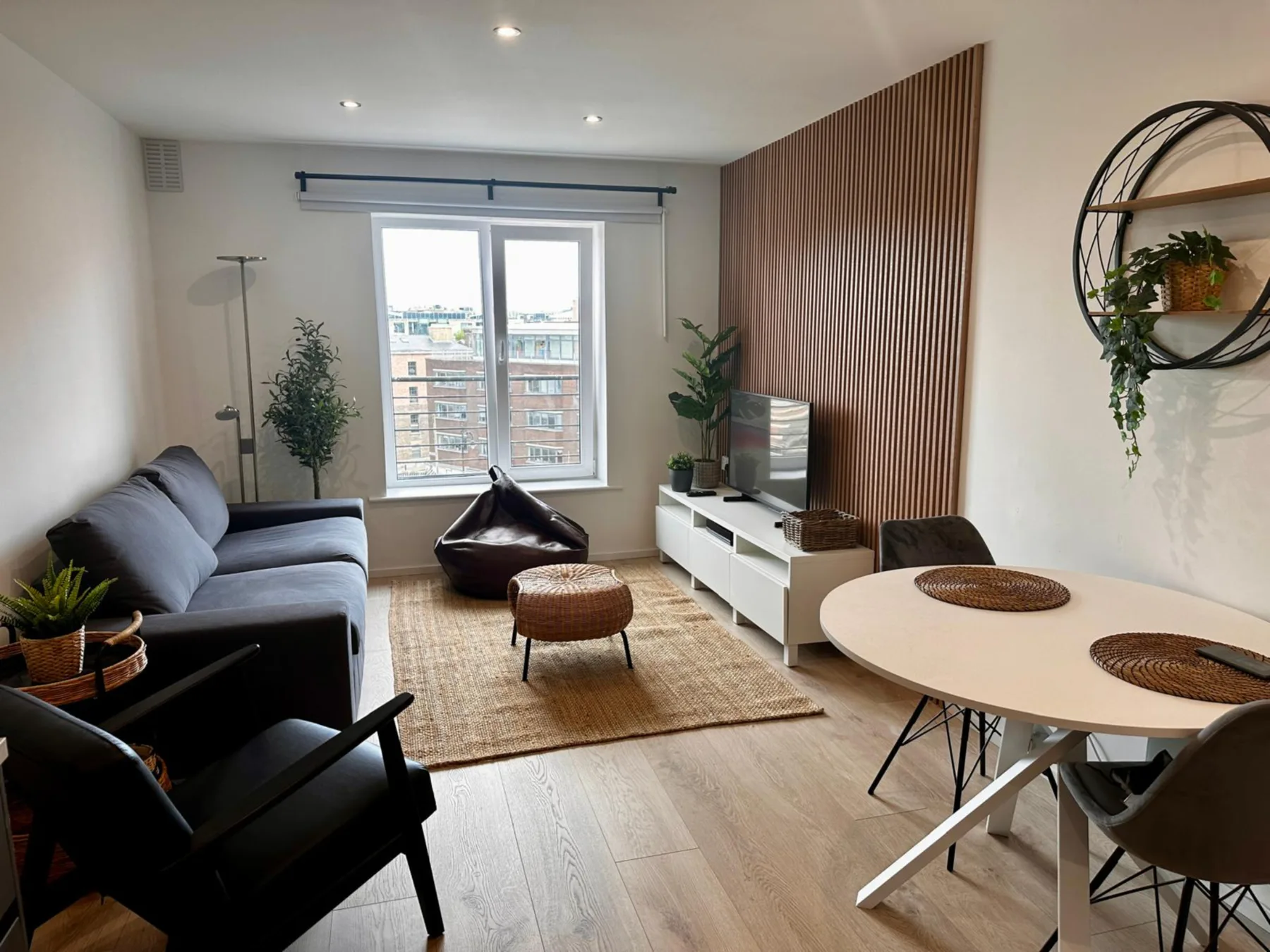 Sala de estar con asientos, una alfombra y una mesa de comedor junto a la ventana.
